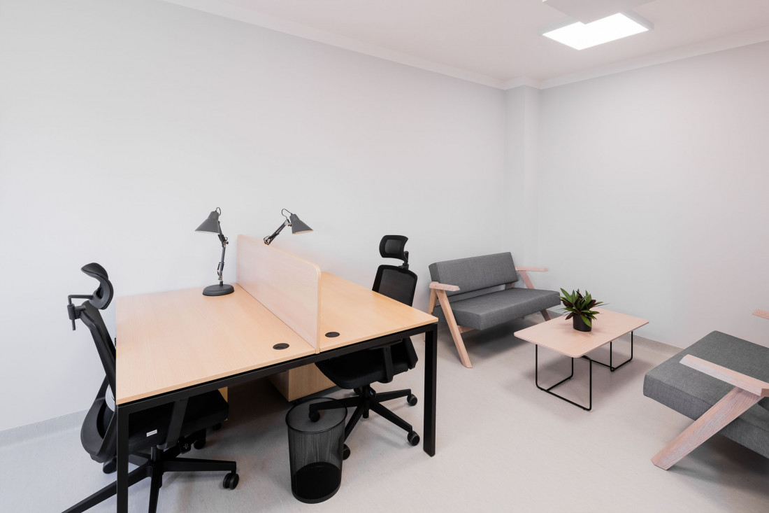widok pomieszczenia biurowego - biurka, krzesła, stolik kawowy